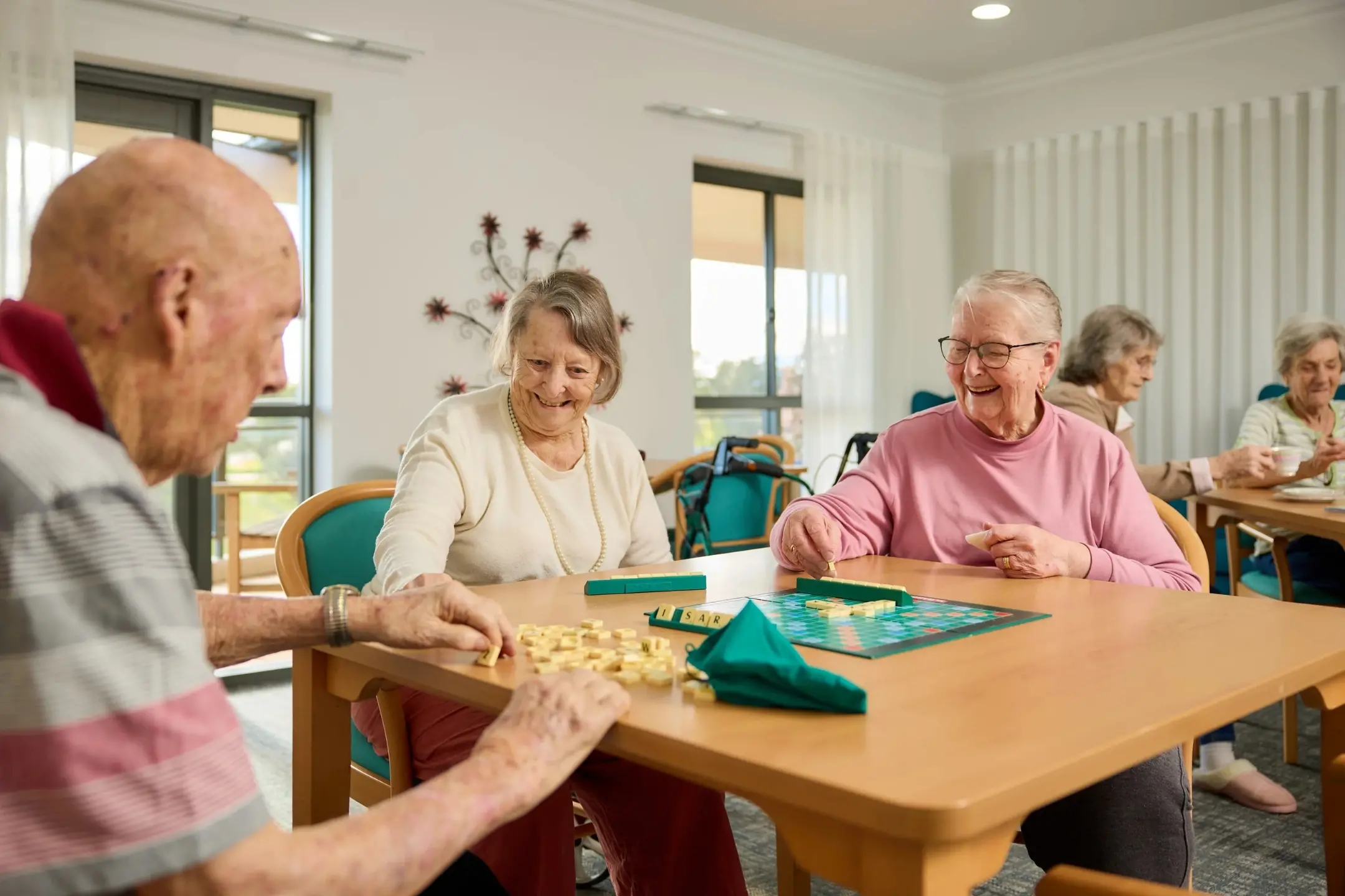 <p>Residents at Southern Cross Care Young Residential Aged Care enjoy a game of scrabble together, highlighting the social activities and opportunities for connection available within the home.</p>\\n